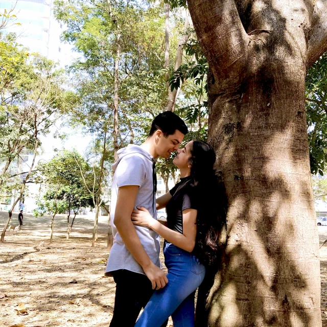 a man and woman kissing by a tree