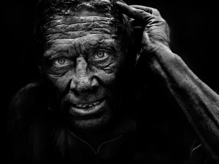 a man holding his head to his ear with mud on his face