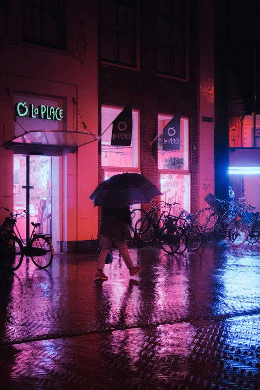 people walking down a street at night, in the rain