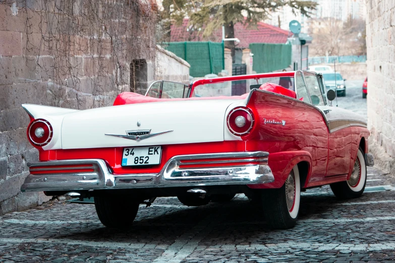 red and white classic car parked in an alley