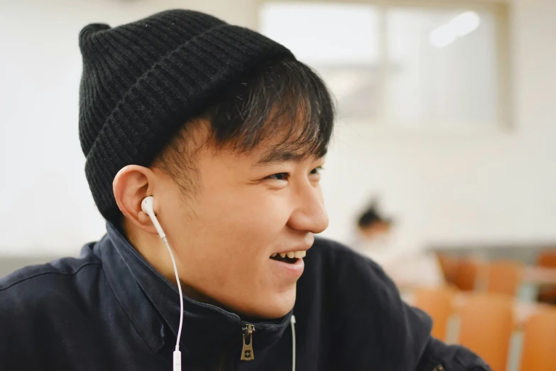 a smiling asian man listening to music in a classroom