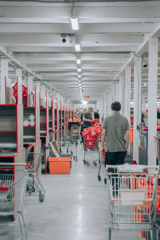 a man is walking down an aisle of supermarket carts