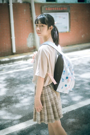 a  walking on a street holding onto her backpack