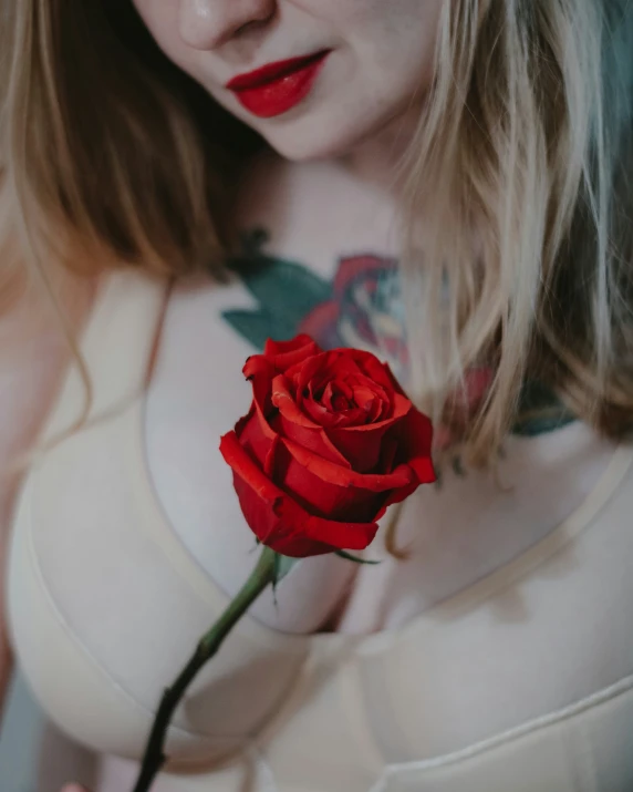 a woman is holding a red rose in her hand