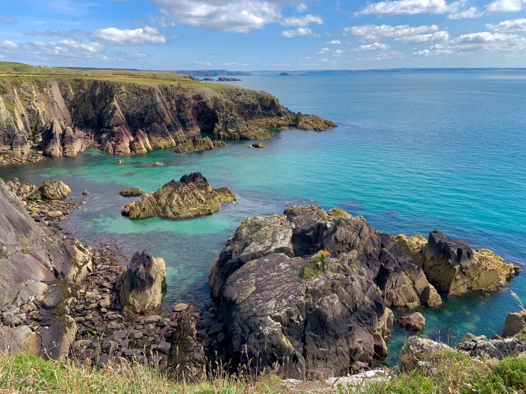 water in a clear blue ocean with a rocky cliff