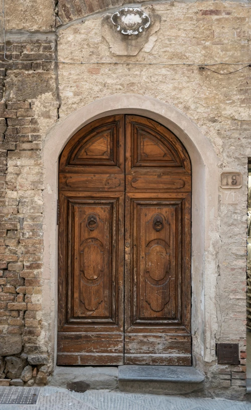 large arched wooden doors on a large stone wall