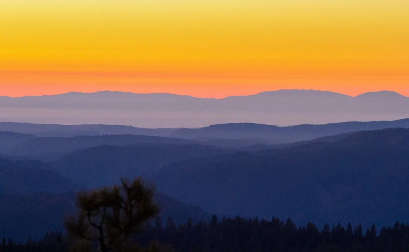 a beautiful sunset over some mountains in the distance