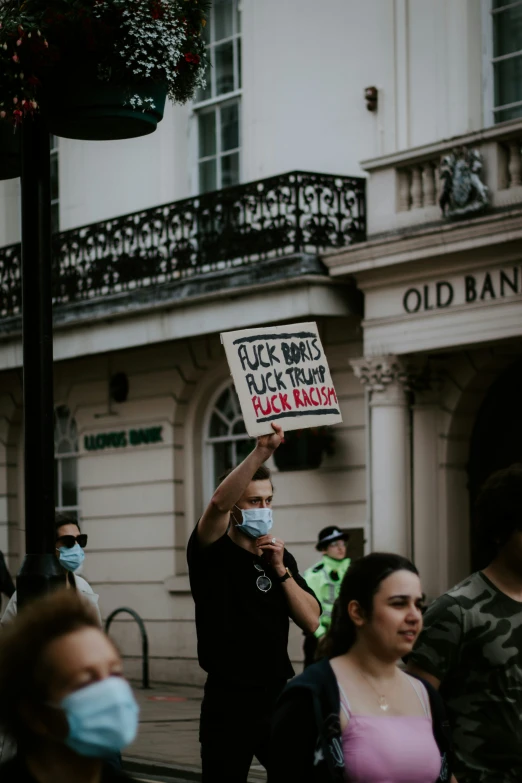 a person holding up a sign that reads fake babies, black trump, black mask