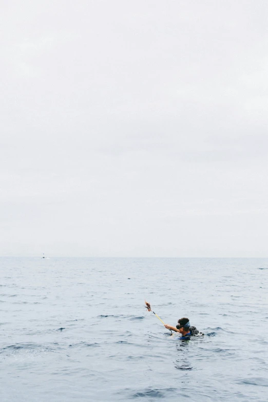 someone floating on their surfboard while holding onto a pole