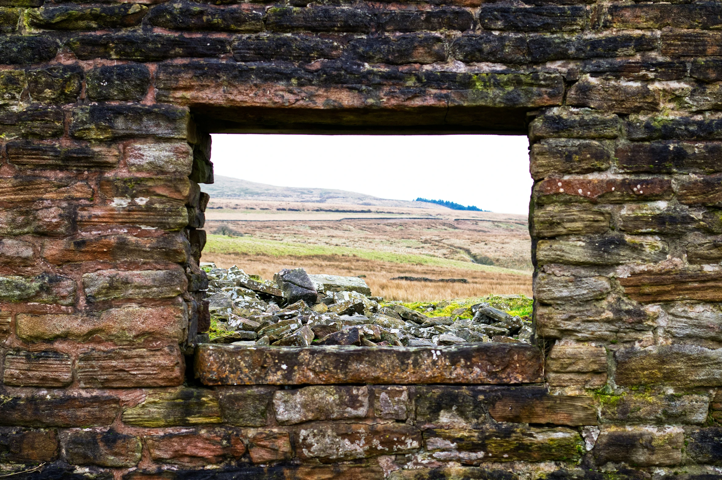 a window into a stone walled structure in the countryside