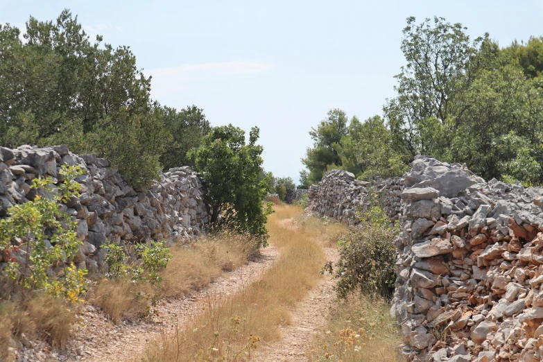 a stone wall by the road that is lined with rocks