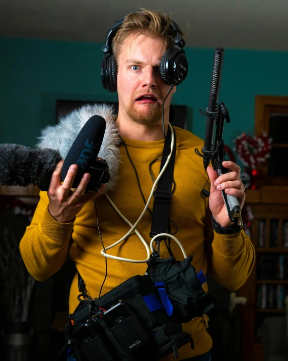 man in headphones holding a gun and camera