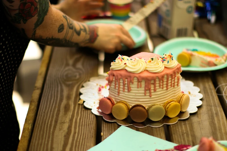 man with tattoo is holding a knife near a small cake