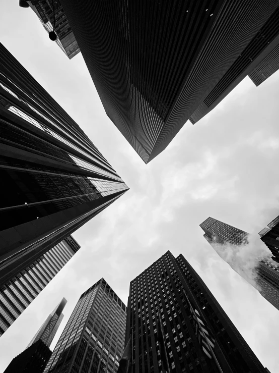 looking up at skyscrs against a cloudy sky