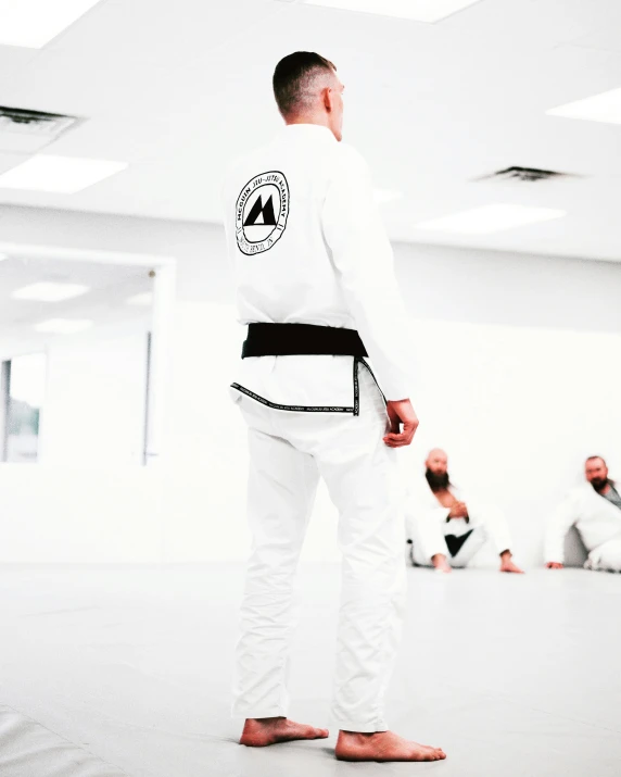 people practicing karate in a room with one man watching