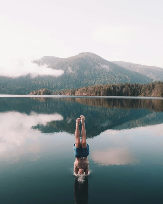 a person is doing yoga on the end of a dock near a body of water