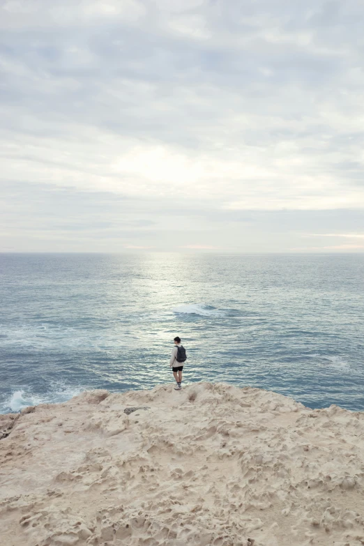 a man standing on top of a sandy beach next to the ocean