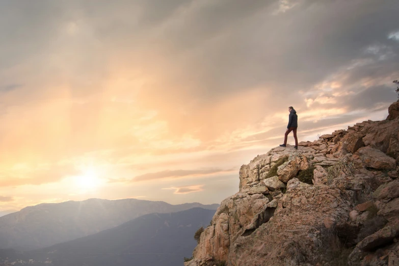 a man standing on a rocky mountain while it rains