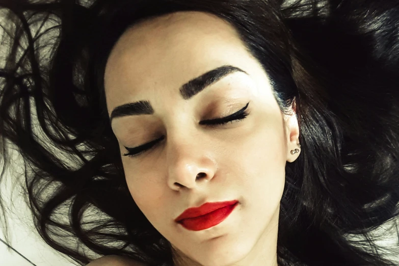 a woman laying down with her eyes closed and closed