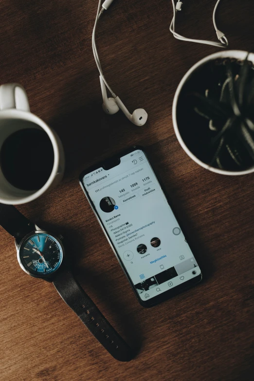 two white cups, a wrist watch and a cellphone on a table