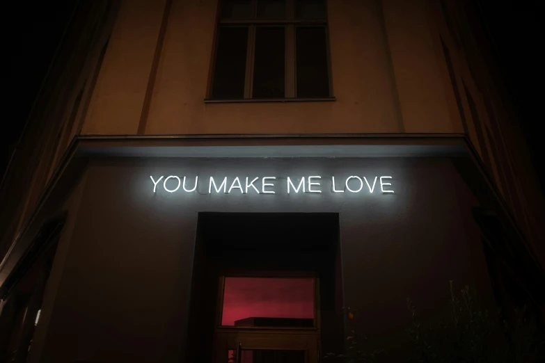 a glowing sign above a building with the word you make me love written on it