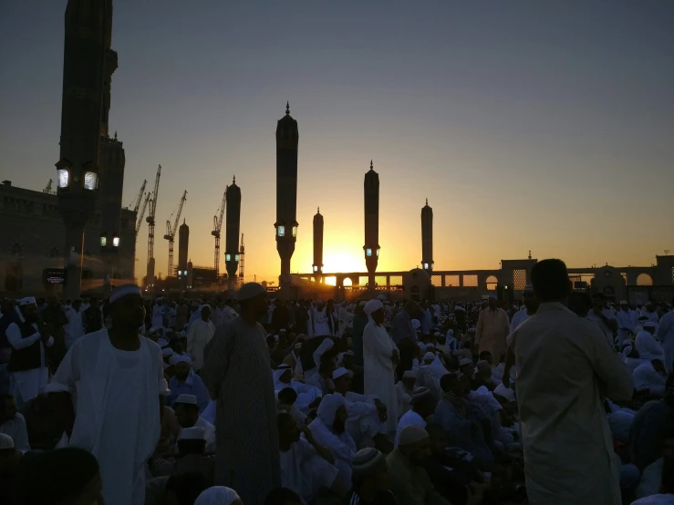 people standing around watching the sunset outside a city