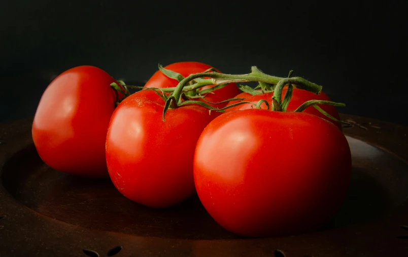 four tomatoes sitting on top of a plate