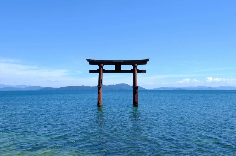 an oriental shrine stands in the middle of a body of water