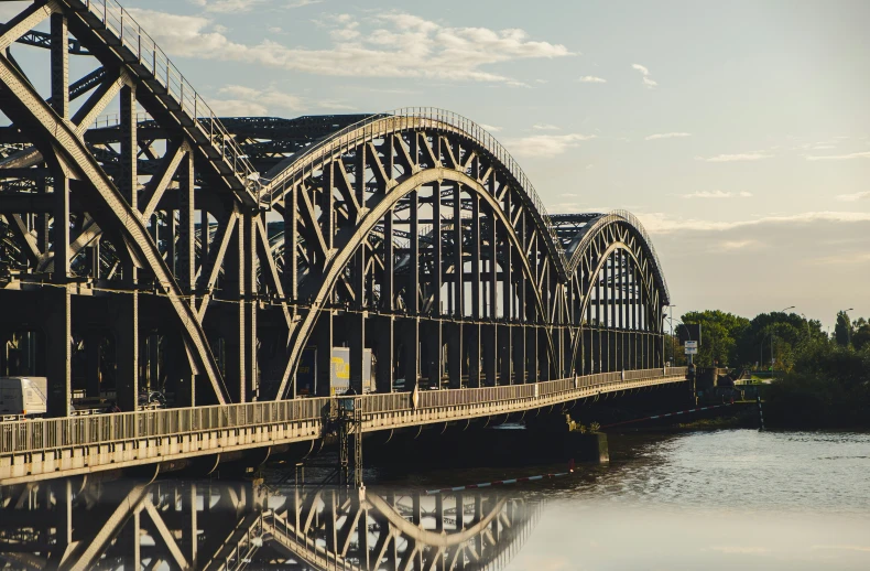 the train bridge is near the water in a park