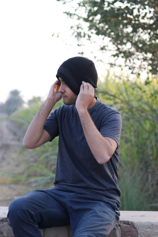 a young man sitting outside talking on his cellphone