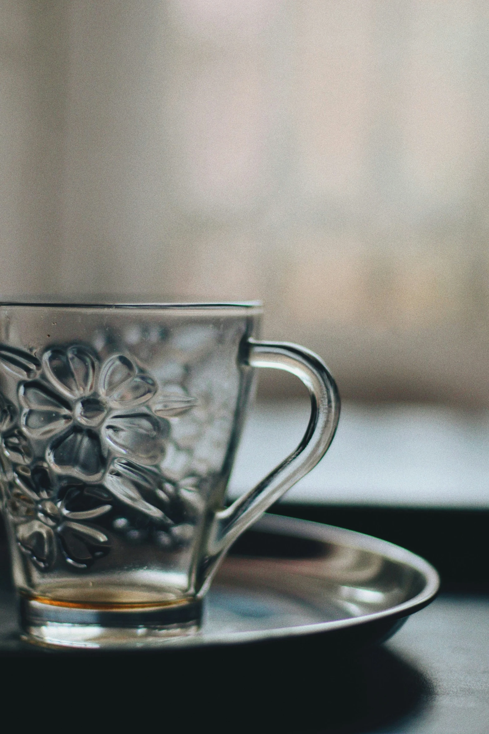 a glass cup with an open saucer on a table