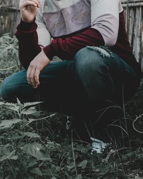 a person with long hair is sitting in a grassy field