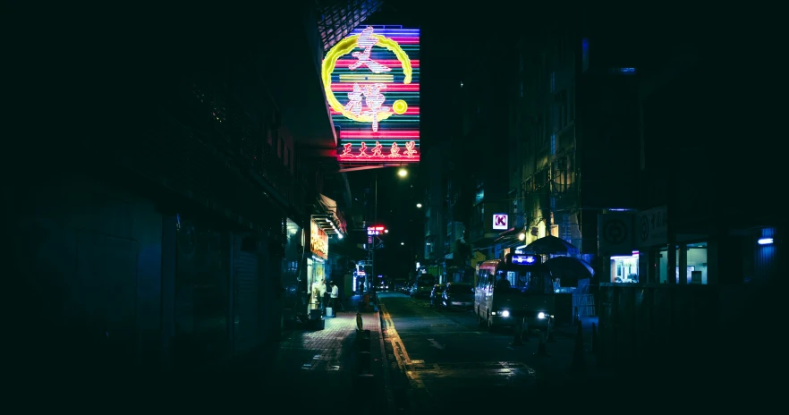 a dimly lit street and building with a lighted advertit in the distance