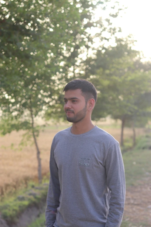 a man standing on dirt path next to trees