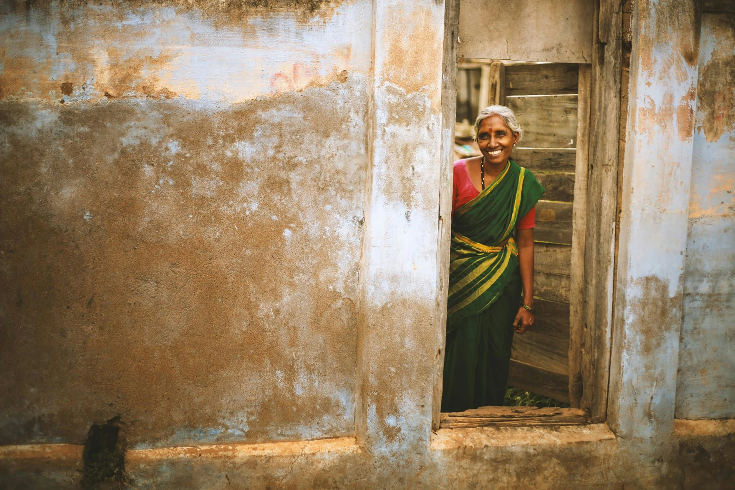 a woman standing in an open window with a cat nearby