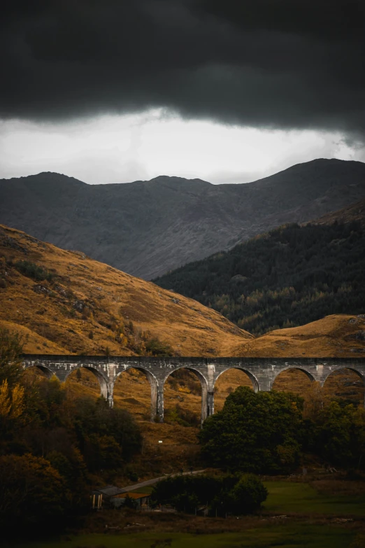 a stone bridge crosses a valley in the mountains