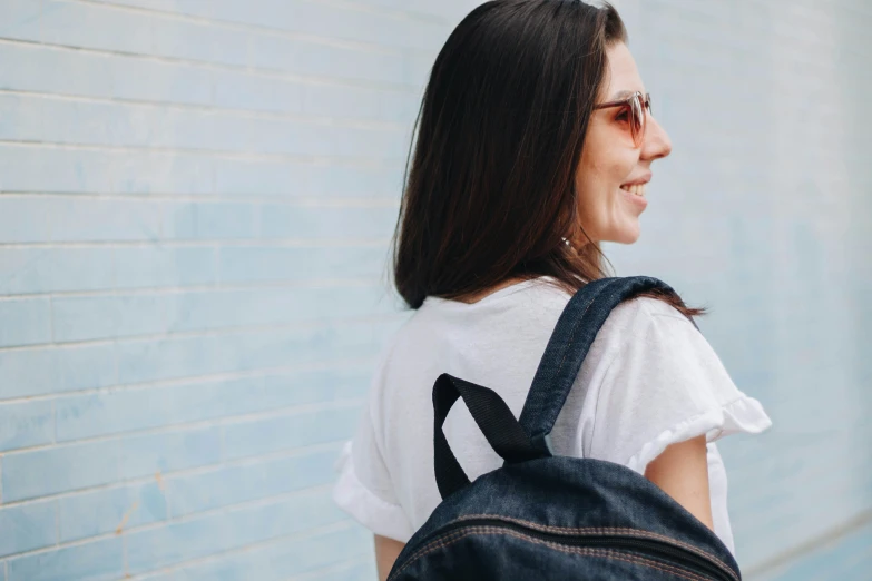 a woman wearing a white t shirt with a black backpack