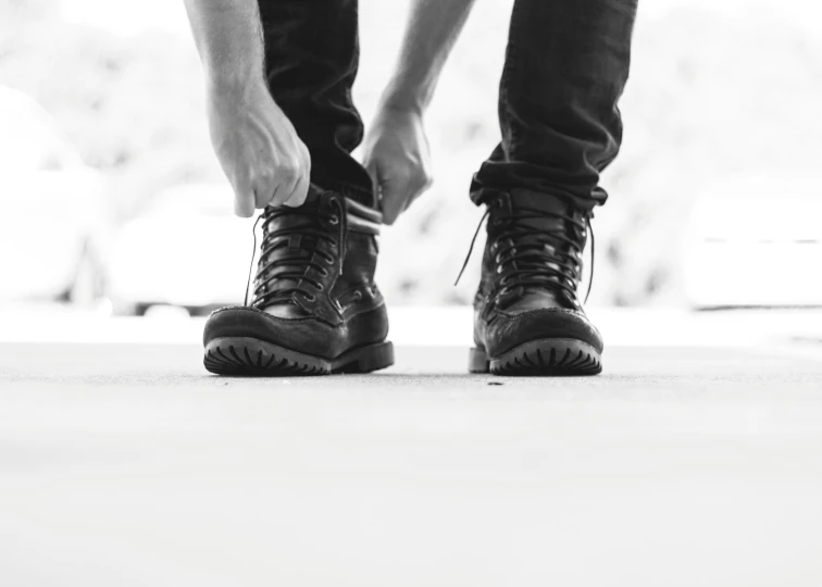 black and white pograph of man standing wearing dark shoes