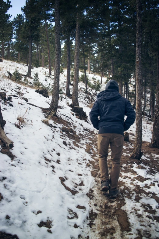 the man is walking on the snow in his blue jacket