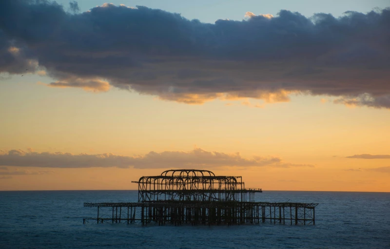 a large structure floating on top of water at sunset