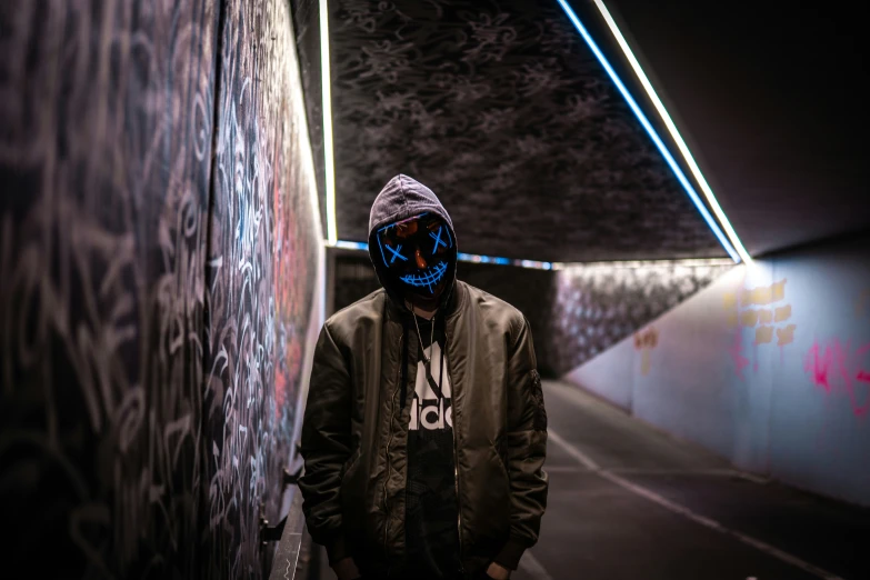 a man standing against a wall covered with graffitti