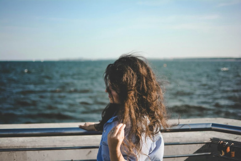 a woman sitting on a pier staring out at the water