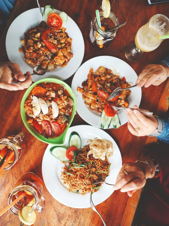 several plates of food with some people eating