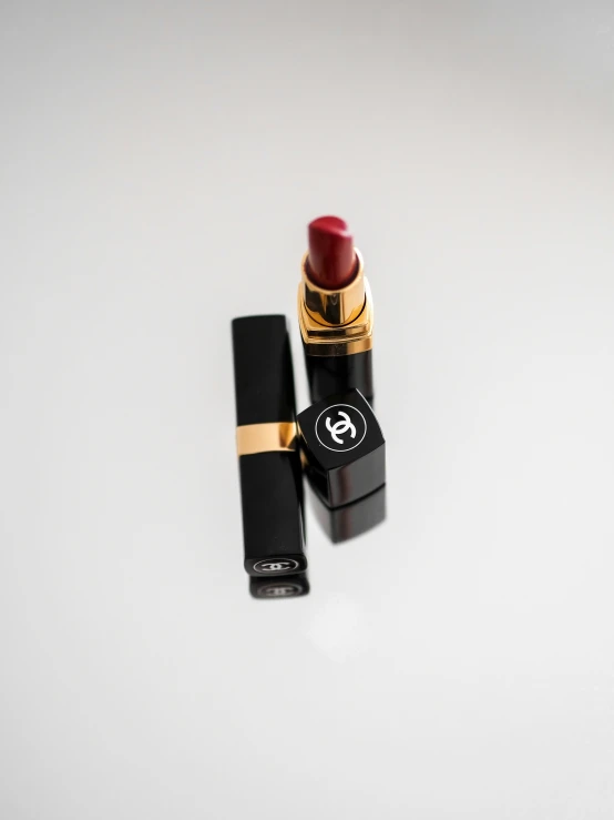 a lipstick is next to another one on a white table