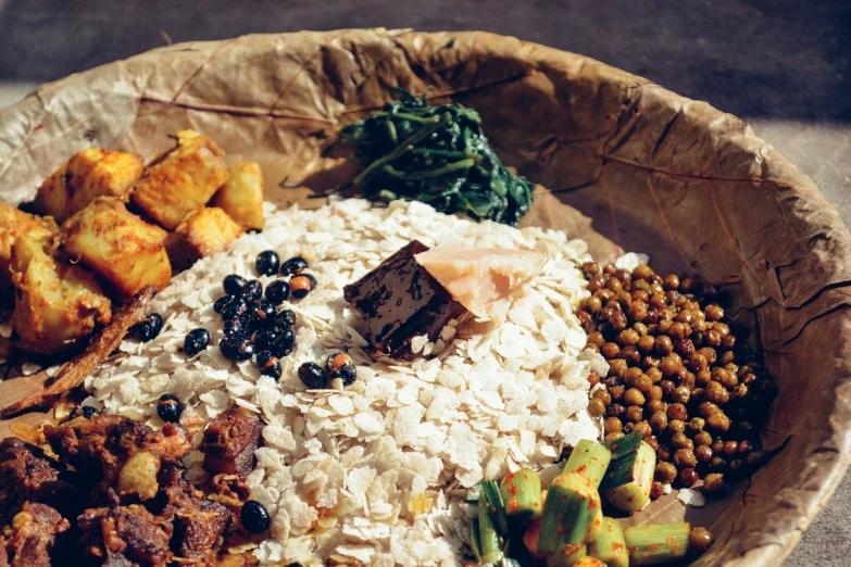 a paper plate with various food items that include rice and greens