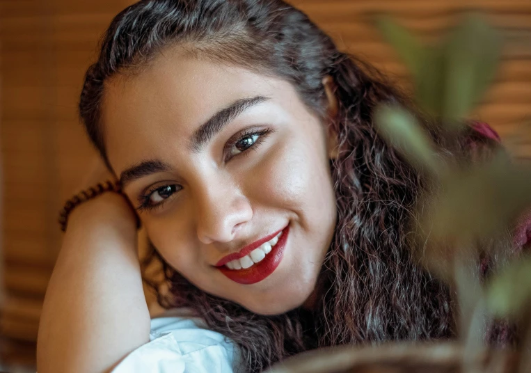 a smiling young woman wearing a blue dress sitting on a couch