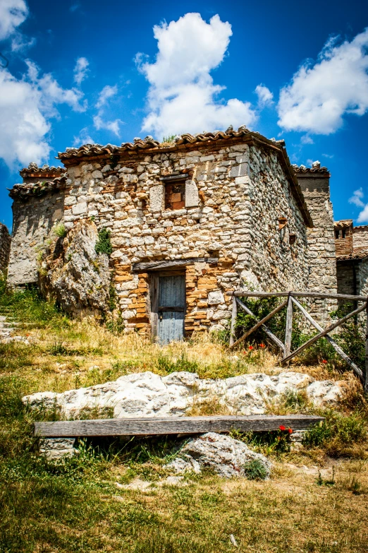 an old house sits near some grass and dirt