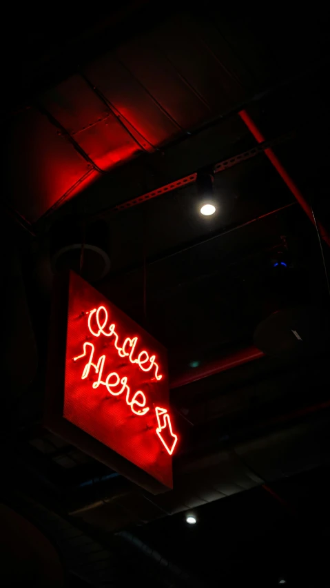 the neon sign is red in a darkened area