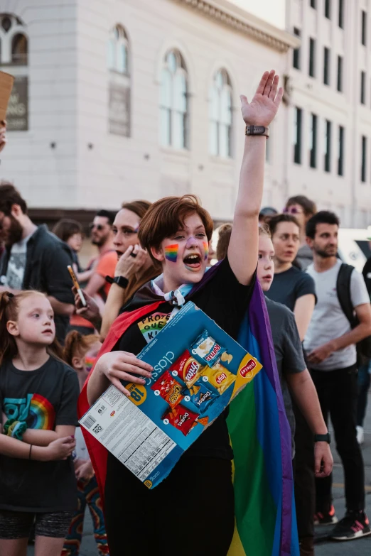 a woman with a large rainbow sign and her hands up