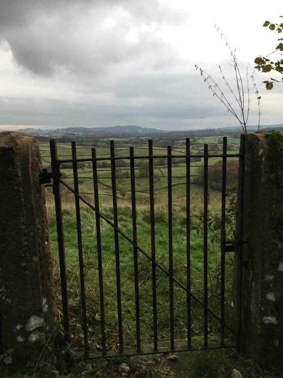 a gate leading to an open field with mountains in the background